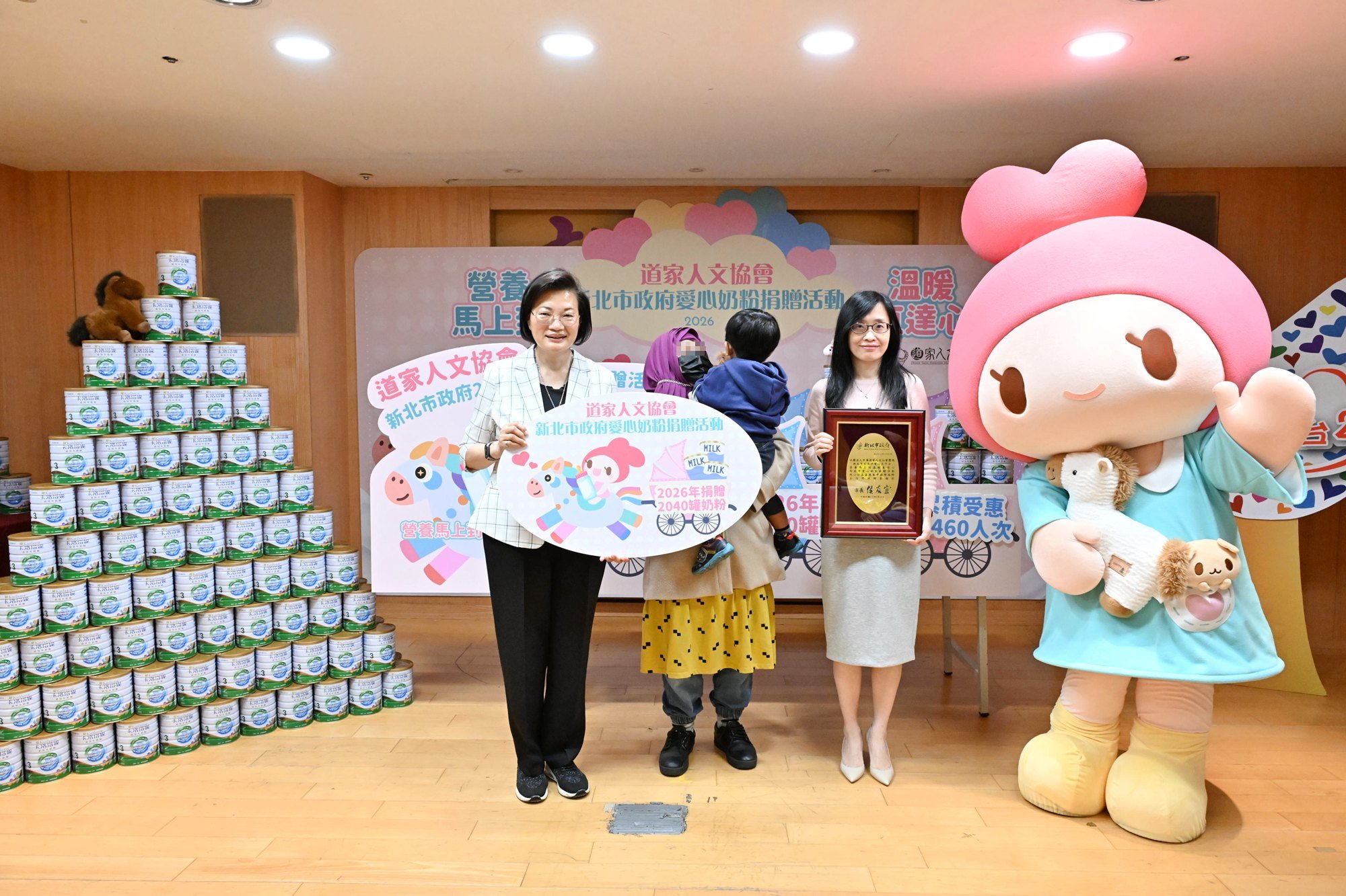 活動儀式上，協會理事長張旖(右二)、新北市社會局局長李美珍(左)及協會公益大使發心娃娃，與家戶代表合影，傳遞誠摯關懷